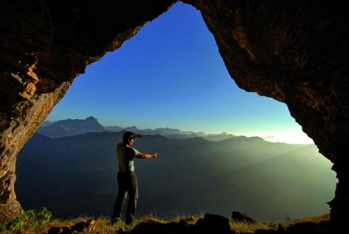 a man standing inside of a cave looking into the sky at Landhaus Almrausch in Mittelberg