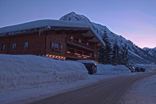 a building covered in snow next to a road at Landhaus Almrausch in Mittelberg
