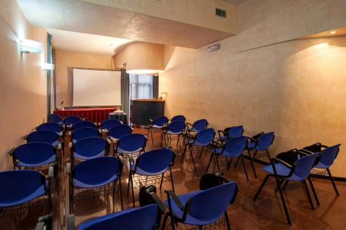a room with a bunch of chairs and a screen at Hotel Granduca SPA & Parking in Grosseto