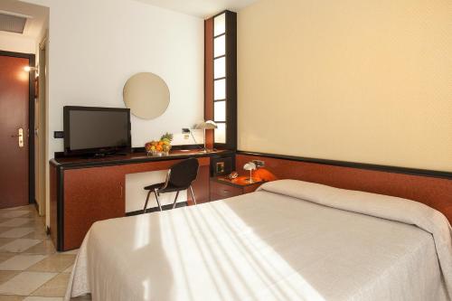 
a hotel room with a bed, tv and a desk at Hotel Granduca in Grosseto
