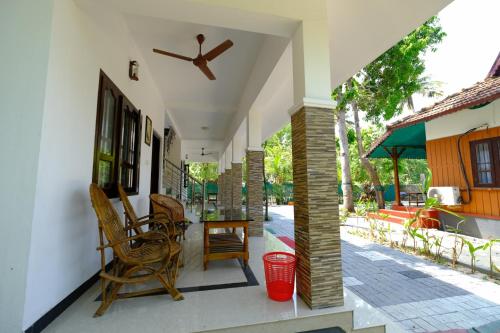 a porch of a house with chairs and a ceiling fan at Marari Arapakal Beach Villa in Mararikulam