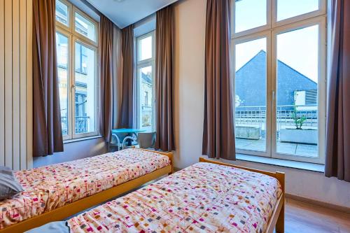 um quarto de hotel com duas camas e janelas em Jacques Brel Youth Hostel em Bruxelas