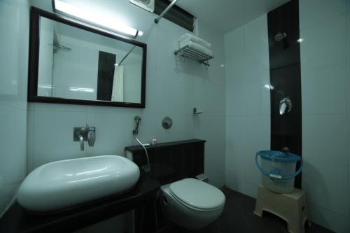 a bathroom with a toilet and a sink and a mirror at Hotel Green Palace in Puducherry