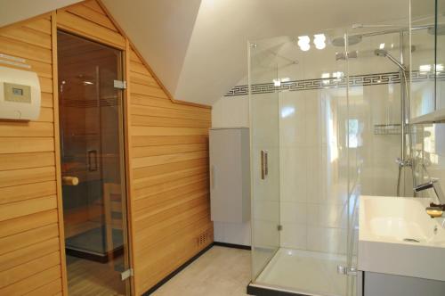 Un baño con ducha de cristal y lavabo. en La Coline, en Somme-Leuze