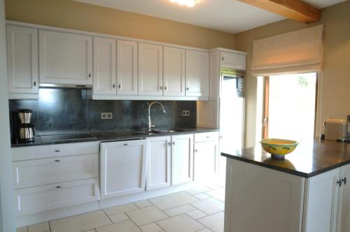 a kitchen with white cabinets and a black counter top at La Coline in Somme-Leuze