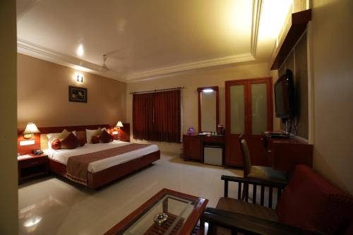 a hotel room with a bed and a living room at Hotel Green Palace in Pondicherry