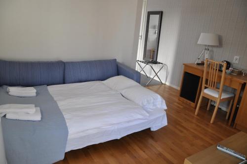a bedroom with a bed with white sheets and a desk at Hotel Bella Luna in Båstad