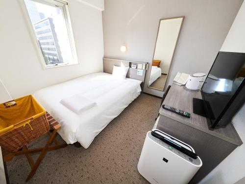 a small hotel room with a bed and a television at Super Hotel Tokyo Nihombashi Mitsukoshimae in Tokyo