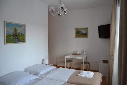 a white bedroom with a bed and a table at Pension Nika in Prague