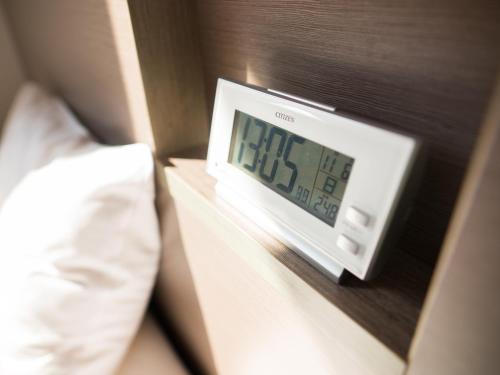 a alarm clock on a night stand next to a bed at Super Hotel Tokyo Nihombashi Mitsukoshimae in Tokyo