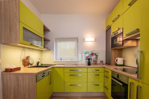 una cocina verde con armarios amarillos y fregadero en Apartment Aloha, en Znojmo