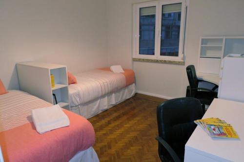 リスボンにあるFérias no Bairroのベッド2台、デスク、椅子が備わる客室です。