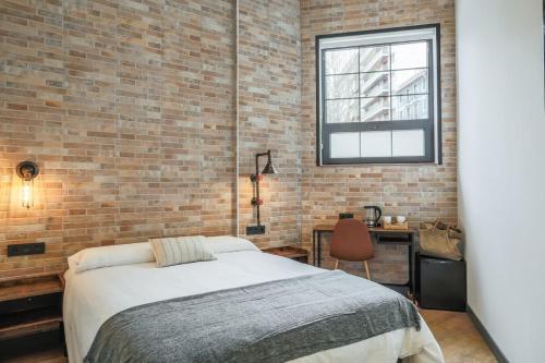 a bedroom with a bed and a brick wall at Pensión H30 Bilbao in Bilbao