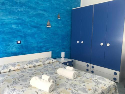 een blauwe slaapkamer met een bed met handdoeken erop bij Divino Bed & Breackfast in Manfredonia