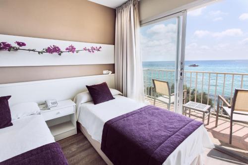 een hotelkamer met 2 bedden en een balkon bij Hotel Brisa Marina in S'Illot