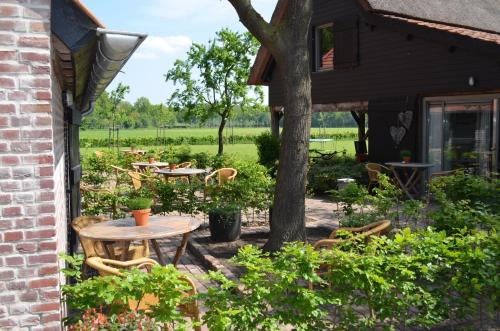 a patio with tables and chairs and a tree at Erfgoed & Logies Den Heijkant in Moergestel