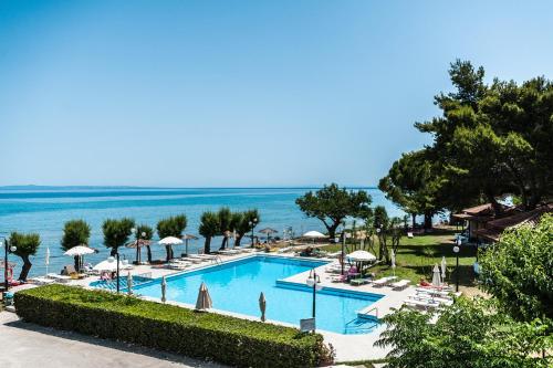 una piscina con sedie e ombrelloni e l'oceano di Mimoza Beach ad Argásion
