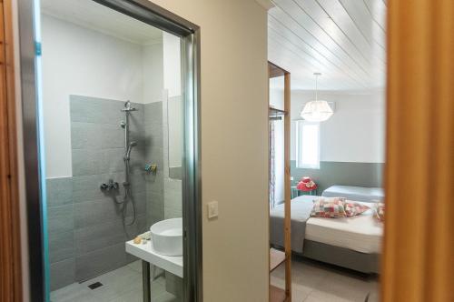 un bagno con doccia, lavandino e letto di Mimoza Beach ad Argásion