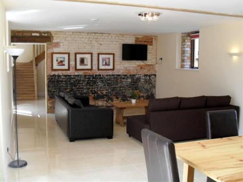 ein Wohnzimmer mit Sofa und Tisch in der Unterkunft Toad Hall at Tove Valley Cottages in Towcester