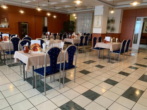 un comedor con mesas blancas y sillas azules en Hotel Patriot, en Vranov nad Topľou