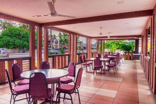 a restaurant with tables and chairs and windows at Myvilla Langkawi Hotel in Pantai Cenang