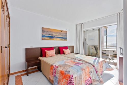 um quarto com uma cama com almofadas vermelhas em AZUL/MAR ALBUFEIRA 602 em Albufeira