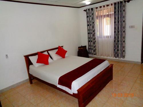a bedroom with a bed with red pillows and a window at Solal Villa in Aluthgama