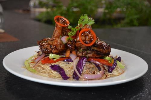 een bord met vlees en noedels op een tafel bij Swosti Palm Resort Gopalpur in Gopālpur