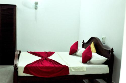 a bedroom with a bed with red and white pillows at Solal Villa in Aluthgama