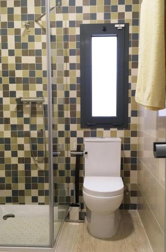 a bathroom with a toilet and a shower with a window at L&F House in Algoz