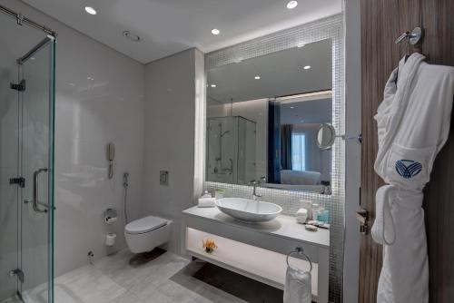 a bathroom with a sink and a toilet and a mirror at Arjaan by Rotana - Dubai Media City in Dubai