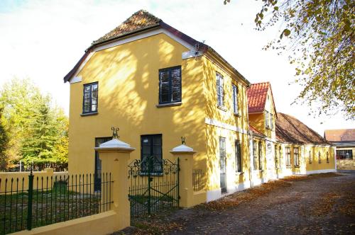 a yellow house with a fence in front of it at Villa Nikolaj - Historisches Pastorat in Fehmarn