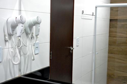 a bathroom with two hair dryers on the wall at Moda Center Hotel in Santa Cruz do Capibaribe