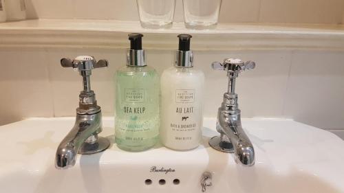 un lavandino con due bottiglie di sapone e due rubinetti di Scooniehill Farm House B&B a St Andrews
