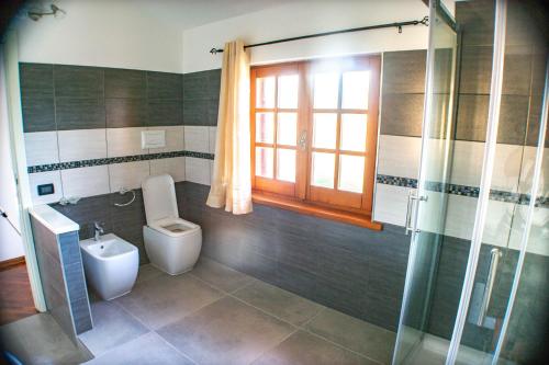 a bathroom with a toilet and a glass shower at Asherat B&B in Carbonia