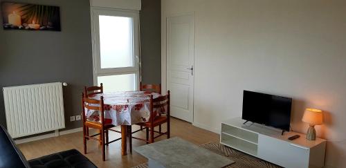 a living room with a table and chairs and a television at t2 lumineux avec balcon in Saint Malo