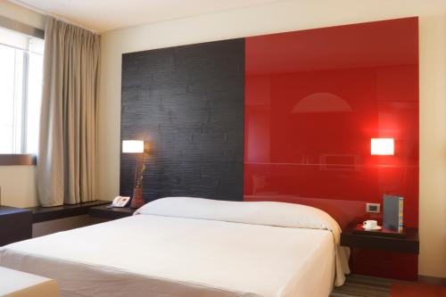 a bedroom with a white bed and a red wall at UNA HOTELS T Hotel Cagliari in Cagliari