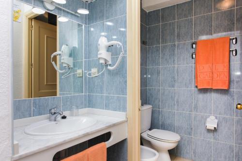 a bathroom with a sink and a toilet and a mirror at Apartamentos Palm Garden by LIVVO in Morro del Jable