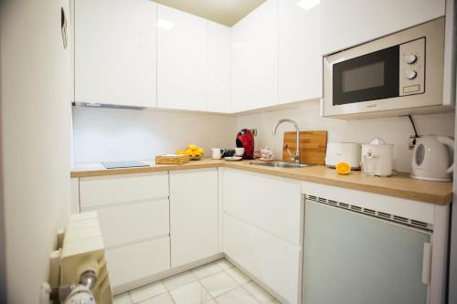 a kitchen with white cabinets and a microwave at Casa Patio del Siglo XIX in Seville