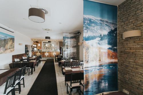 a restaurant with tables and chairs and a wall at Hotel Majerzanka in Piwniczna
