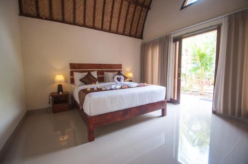 a bedroom with a bed and a large window at The Penida Bungalow in Nusa Penida