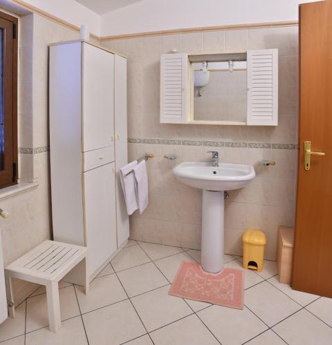 a white bathroom with a sink and a mirror at B&B Mitzixeddas in Màndas