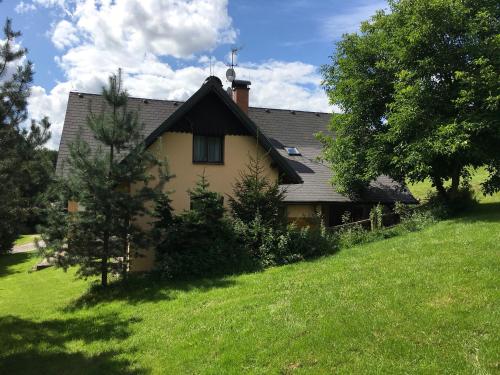 ein Haus auf einem Hügel mit einem grünen Feld und Bäumen in der Unterkunft Chalupa Herman in Rudník