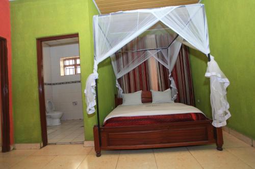 a bedroom with a canopy bed and a bathroom at La Voisina Hotel in Ruhengeri