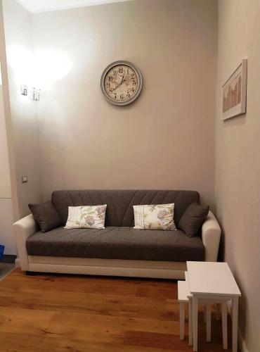 a couch in a living room with a clock on the wall at Casa De Rose in Rome