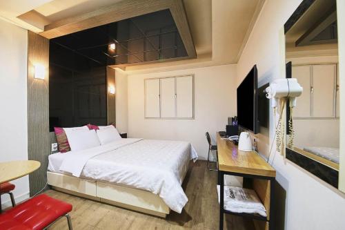um quarto com uma cama, uma mesa e uma televisão em K2 Motel em Seul