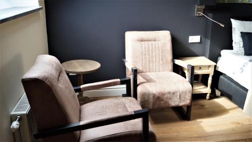 a room with two chairs and a table and a bed at B&B Johannes-Hoeve in Baarlo