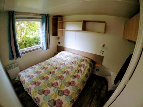 a small bedroom with a bed and a window at Mobile Home Climatisé in Les Mathes