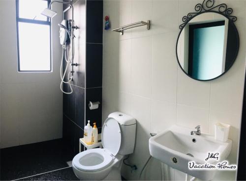 a bathroom with a toilet and a sink and a mirror at Santorini by J&G Vacation Homes in Skudai