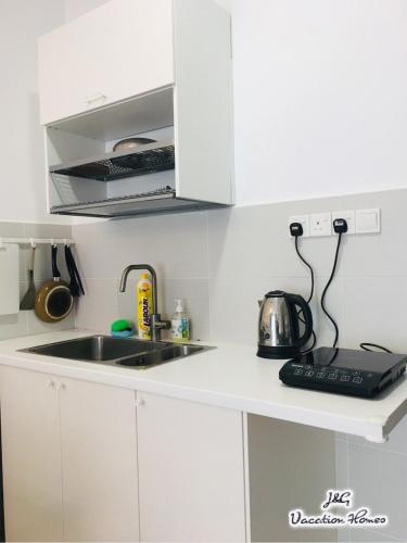a white kitchen with a sink and a microwave at Santorini by J&G Vacation Homes in Skudai